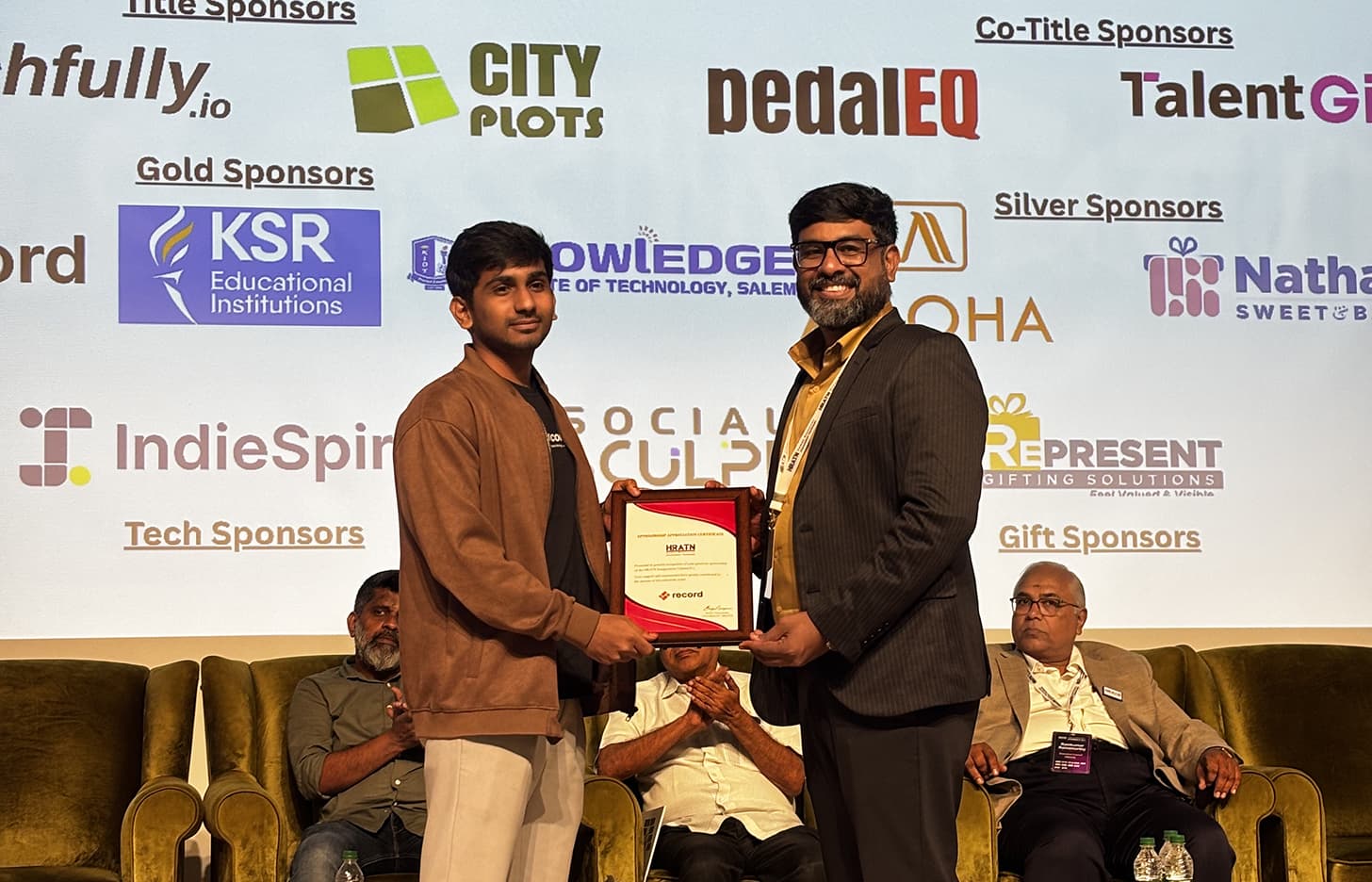 Record receiving a sponsor appreciation certificate on stage